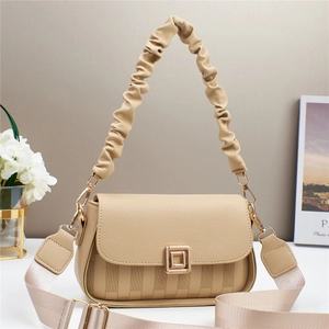 Detail of beige embossed crossbody bag featuring a ruched handle and wide fabric strap