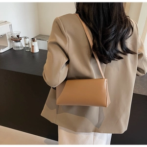Chic camel faux leather baguette bag worn over the shoulder by a model in a blazer