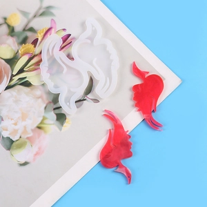 Detail of bird-shaped silicone molds and finished red resin earrings on floral paper