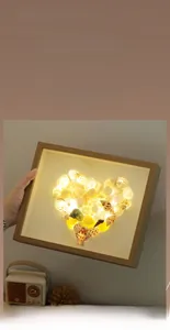 Detail of DIY wooden light frame featuring natural seashells in a warm heart shape