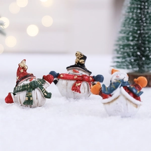 Three creative Christmas snowman figurines with colorful scarves on fake snow background