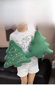 Detail of soft plush Christmas tree pillows with colorful embroidery in a cozy home setting