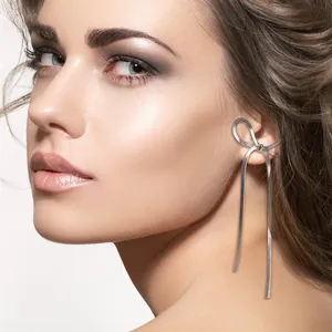 Detail of silver bow tassel earrings featuring elegant snake chain style on a model
