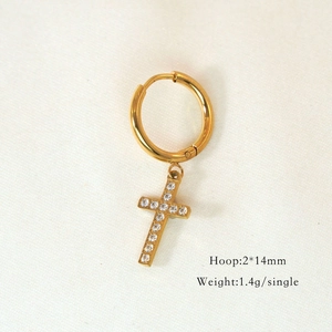 Macro shot of 2x14mm gold cross hoop earring with white zircon on white textured fabric