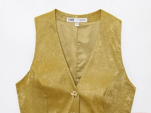 Dettaglio macro del gilet di velluto giallo con bottone dorato ed etichetta taglia