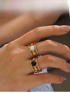 Detail of 18K gold plated rings with shell relief and white and black gemstones