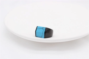 Top view of a square men's ring with turquoise stone inlay on a white ceramic plate