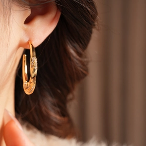 Detailed close-up of 18K gold plated C-shaped twisted earrings with sparkling zircons