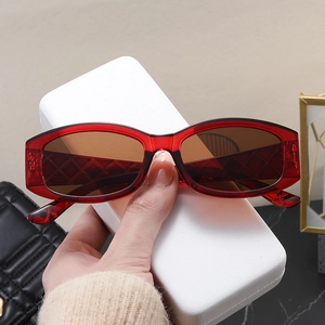 Detail of red transparent oval sunglasses with quilted texture temples and brown lenses