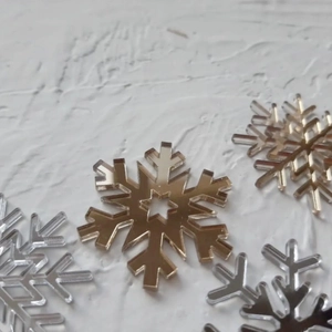 Macro detail of four acrylic snowflake cake toppers with mirror gold and silver finishes