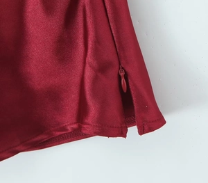 Detalle del tejido de satén rojo vino con cremallera invisible y abertura lateral