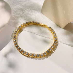 Bohemian gold tennis anklet with round zircon stones on minimalist textured background