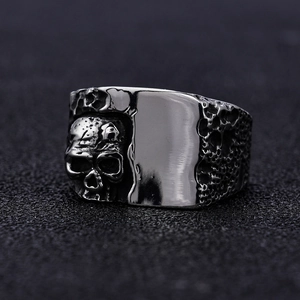 Vintage stainless steel skull ring with gothic embossed design on dark textured background