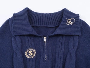 Detail of navy knit polo sweater featuring cable stitch and gold embroidery details