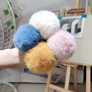 Detailed close-up of colorful plush faux fur pom-pom hair ties in yellow, pink, and blue