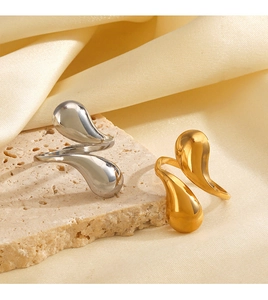 Close-up of minimalist teardrop rings in 18K gold and silver on a silk background