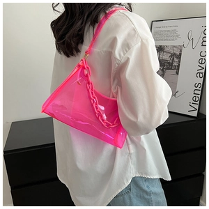 Close-up of neon pink semi-transparent PVC underarm bag with matching thick chain strap