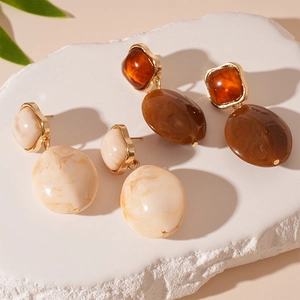 Retro resin geometric earrings with marble texture and amber finish on stone pedestal