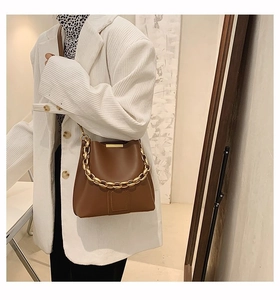 Close-up of brown bucket bag featuring a thick gold decorative chain and smooth leather texture