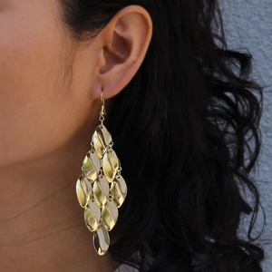 Detailed view of layered gold metal sequin drop earrings on model for a boho look