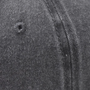 Macro detail of dark grey cotton twill fabric with stitching and eyelet on baseball cap