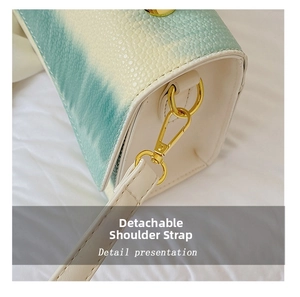 Detail view of a blue gradient crossbody bag with a detachable golden lobster clasp strap