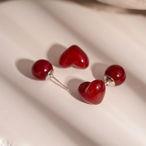 Red resin heart stud earrings with round bead back design on textured background