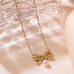 Elegant gold titanium steel necklace featuring a bow pendant and white pearl charm