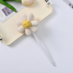 Detail of creative ballpoint pen with white plush smiley daisy flower on creamy tray