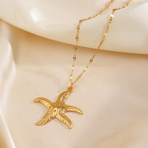 Elegant gold starfish pendant necklace displayed on a beige silk background for women