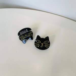 Detail of black glittery cat-shaped hair claw clips with yellow facial accents