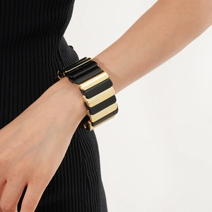 Detail of wide elastic bracelet with black and gold geometric block patterns on wrist