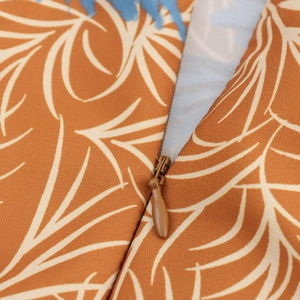Close-up of the invisible zipper and coconut tree leaf print on a brown dress