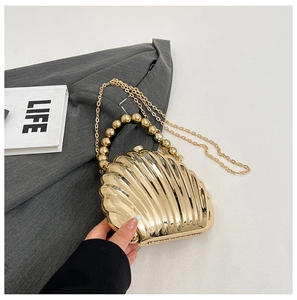 Detail of a golden shell-shaped evening bag with a pearl bead handle and chain strap