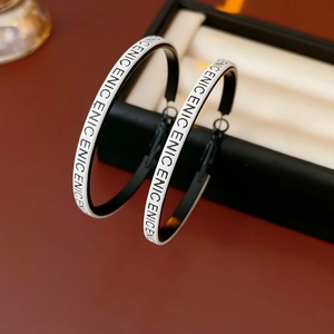 Gros plan de créoles en cuir noir et blanc avec motifs de lettres sur métal