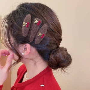 Detail of three plush triangle hair clips with cherry motifs on model's hair