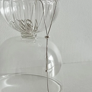 Detail of adjustable silver snake chain necklace with bead slider on glass bowl