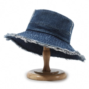 Retro deep blue denim bucket hat with frayed edges on minimalist wooden stand