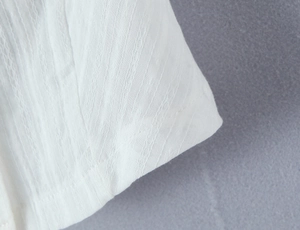 Close-up of white textured seersucker fabric with detailed vertical pleated patterns