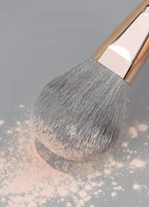 Close-up of fluffy powder brush head with pink powder showing soft fiber bristles