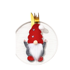 Christmas gnome cutlery holder with red heart hat on a white plate with gold utensils