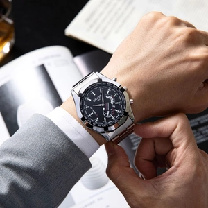 Close-up of a silver men's watch with black dial and chronographs on a male wrist