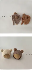 Detailed view of plush baby earflap hat with bear pom-poms and side wooden button