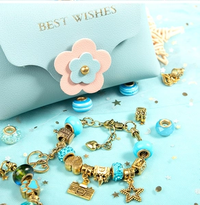 Detail of light blue PU jewelry bag with gold charms, beads and floral snap closure