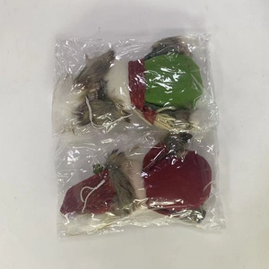 Detail of red and green plush Christmas gnome ornaments in protective plastic packaging