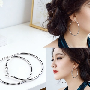 Detail view and model wearing large silver-toned minimalist hoop earrings on white background