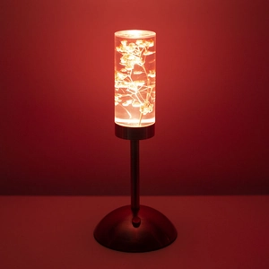 Detailed view of warm LED light shining through preserved flowers in a glass cylinder
