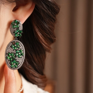 Macro shot of vintage emerald flower earrings with cubic zirconia on a female model