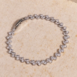 Detail of silver bracelet with marquise and round cut zircons on beige canvas