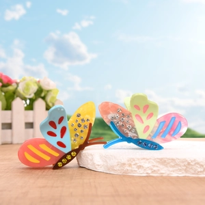 Dual butterfly hair claws with colorful acetate and sparkling rhinestones on stone stand
